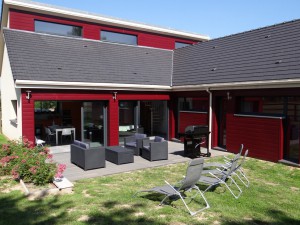 maison rouge avec salon de jardin sur la terrasse du Gîte Le Val Anger à Trouville-la-Haule